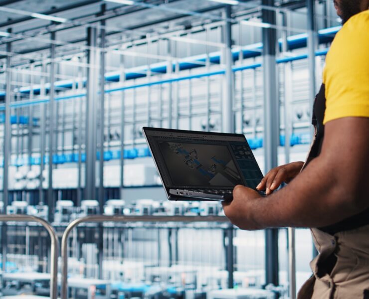 Industry 4.0 industrial plant specialist designs new robotic machines using CAD software on laptop. Smart factory technician using notebook to do tooling for automation equipment, camera A close up