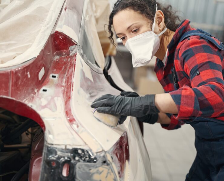Young mechanic in protective mask working in modern service station